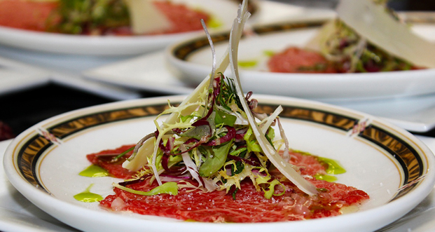 This is a collaboration by Old Homestead Steakhouse Executive Chef Oscar Martinez and Gunma Prefecture, Japan, Wagyu Farmer Katsuya Kato -- Prized Wagyu Sirloin Carpaccio, Bouquet of Greens, Herb Vinaigrette Fusion.